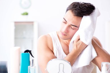 Genç yakışıklı adam aynaya bakıyor. 