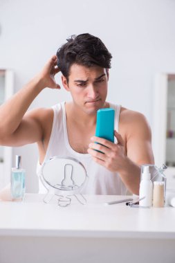 Genç yakışıklı adam aynaya bakıyor. 