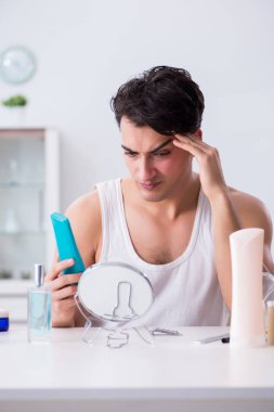 Genç yakışıklı adam aynaya bakıyor. 