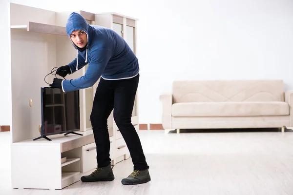 Człowiek włamywacz kradnie telewizor z domu — Zdjęcie stockowe