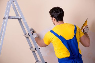 Duvara alçı yapıştıran genç müteahhit.