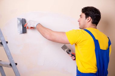 Duvara alçı yapıştıran genç müteahhit.