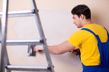 Duvara alçı yapıştıran genç müteahhit.