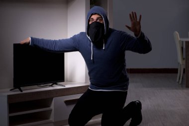 Hırsız, apartmandan televizyon çalıyor.