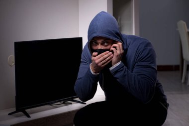 Hırsız, apartmandan televizyon çalıyor.