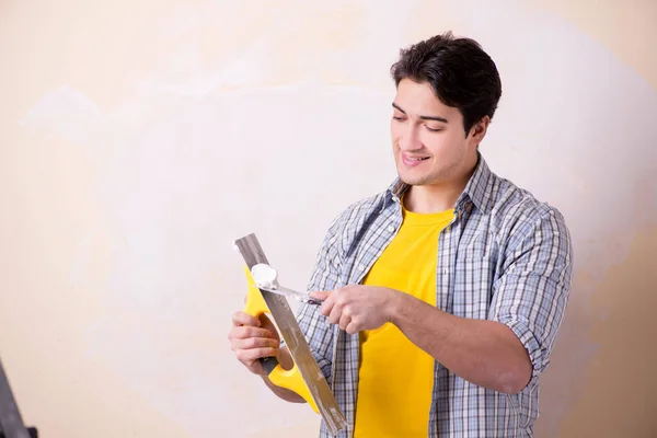 Hombre joven aplicando yeso en la pared en casa — Foto de Stock