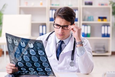 Genç doktor klinikteki röntgen görüntülerine bakıyor.