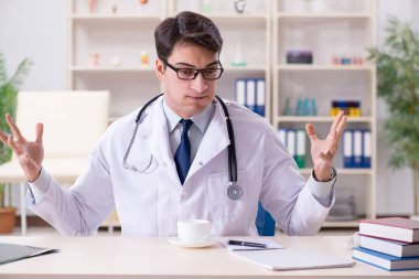 Genç doktor ofiste oturuyor.