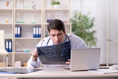 Genç doktor klinikteki röntgen görüntülerine bakıyor.