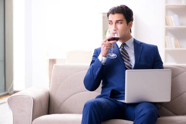 İş adamı evde oturmuş şarap içiyor.