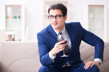 İş adamı evde oturmuş şarap içiyor.