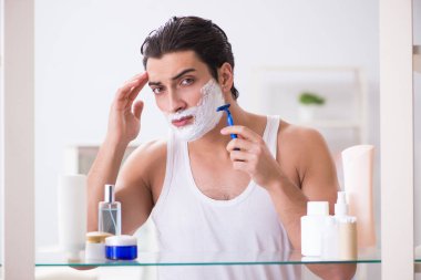 Genç yakışıklı adam sabah erkenden tıraş oluyor.