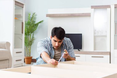 Adam evde mobilya montajı yapıyor.