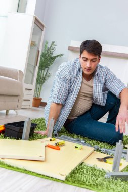 Adam evde mobilya montajı yapıyor.