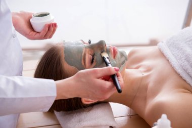 Yüz maskeli, spa sağlık konsepti olan genç bir kadın.