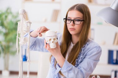 Öğrenci sınıfında oturuyor ve iskelet çalışıyor.