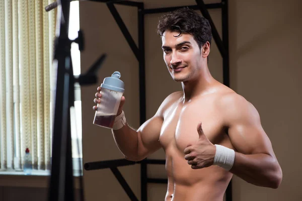 Homem com suplementos nutricionais no ginásio desportivo — Fotografia de Stock