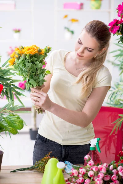 Bahçesinde çiçekleri sulayan genç bir kadın.