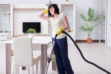 Yaşlı kadın elektrik süpürgesinden yorgun düştü.