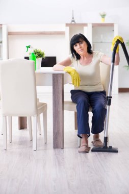 Yaşlı kadın elektrik süpürgesinden yorgun düştü.