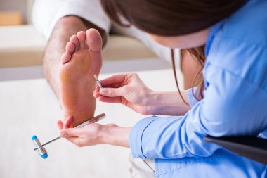 Doktor çekiçle sinir reflekslerini kontrol ediyor