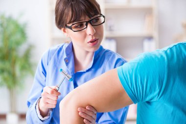 Doktor çekiçle sinir reflekslerini kontrol ediyor