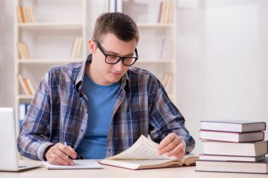 Okul sınavlarına kitaplarla hazırlanan genç bir öğrenci.