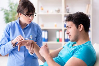 Doktor çekiçle sinir reflekslerini kontrol ediyor