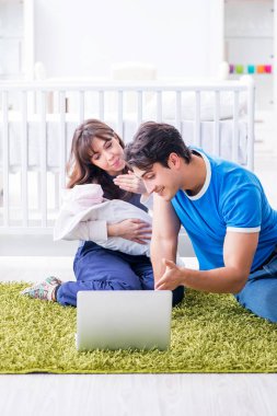 Yeni doğmuş bebekleriyle halıda oturan genç ebeveynler. 