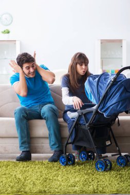 Bebekleri bebek arabasında kanepede oturan genç ebeveynler. 