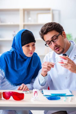 Diş hekimi ve asistanı yeni diş implantı üzerinde çalışıyor.