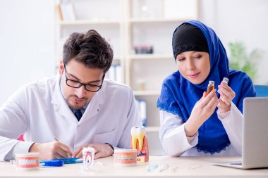 Diş hekimi ve asistanı yeni diş implantı üzerinde çalışıyor.