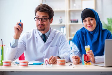 Diş hekimi ve asistanı yeni diş implantı üzerinde çalışıyor.