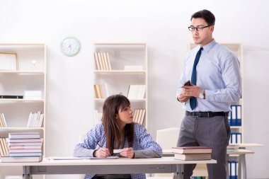 Erkek öğretim görevlisi bayan öğrenciye ders veriyor.