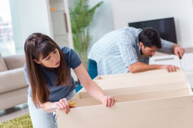 Yeni evde mobilya montajı yapan genç bir aile.