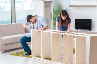 Yeni evde mobilya montajı yapan genç bir aile.