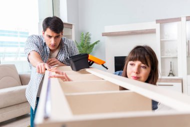 Yeni evde mobilya montajı yapan genç bir aile.