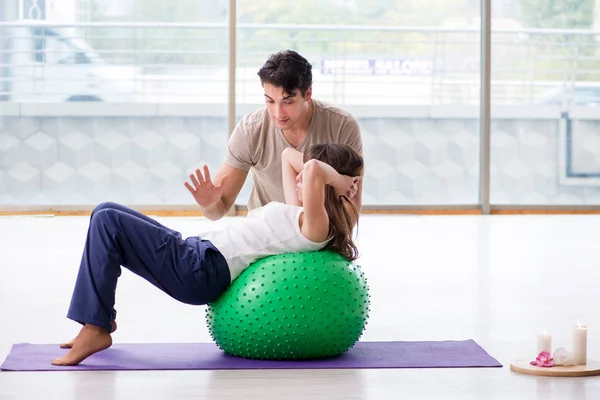 Personal Coach hilft Frau im Fitnessstudio mit Stabilitätsball — Stockfoto