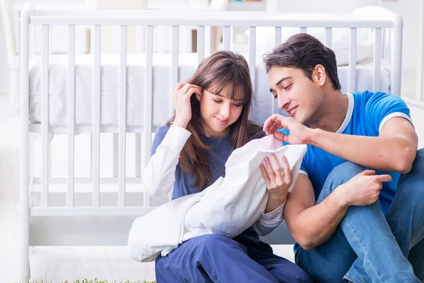 Padres jóvenes con su bebé recién nacido sentado en la alfombra — Foto de Stock