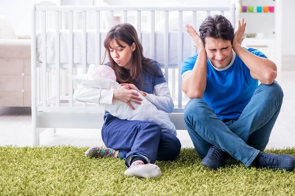 Jonge ouders met hun pasgeboren baby zittend op het tapijt — Stockfoto