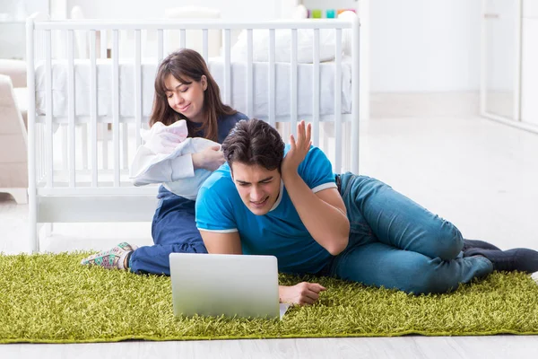 Yeni doğmuş bebekleriyle halıda oturan genç ebeveynler. 