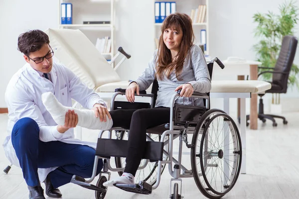 Врач-мужчина осматривает пациентку на инвалидном кресле — стоковое фото