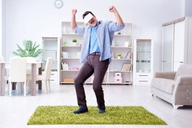 Evde sanal gerçeklik gözlüklü bir adam oynuyor.