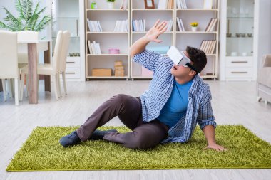 Evde sanal gerçeklik gözlüklü bir adam oynuyor.