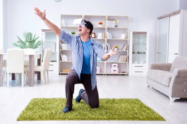 Evde sanal gerçeklik gözlüklü bir adam oynuyor.