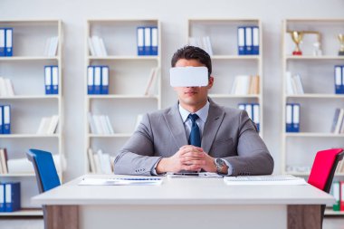 Ofiste sanal gerçeklik gözlüklü bir iş adamı var.