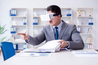 Ofiste sanal gerçeklik gözlüklü bir iş adamı var.
