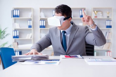 Ofiste sanal gerçeklik gözlüklü bir iş adamı var.