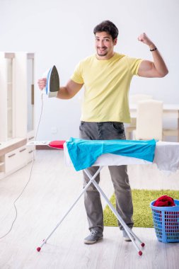 Yakışıklı koca evde kıyafet ütülüyor.