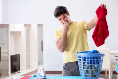 Yakışıklı koca evde kıyafet ütülüyor.